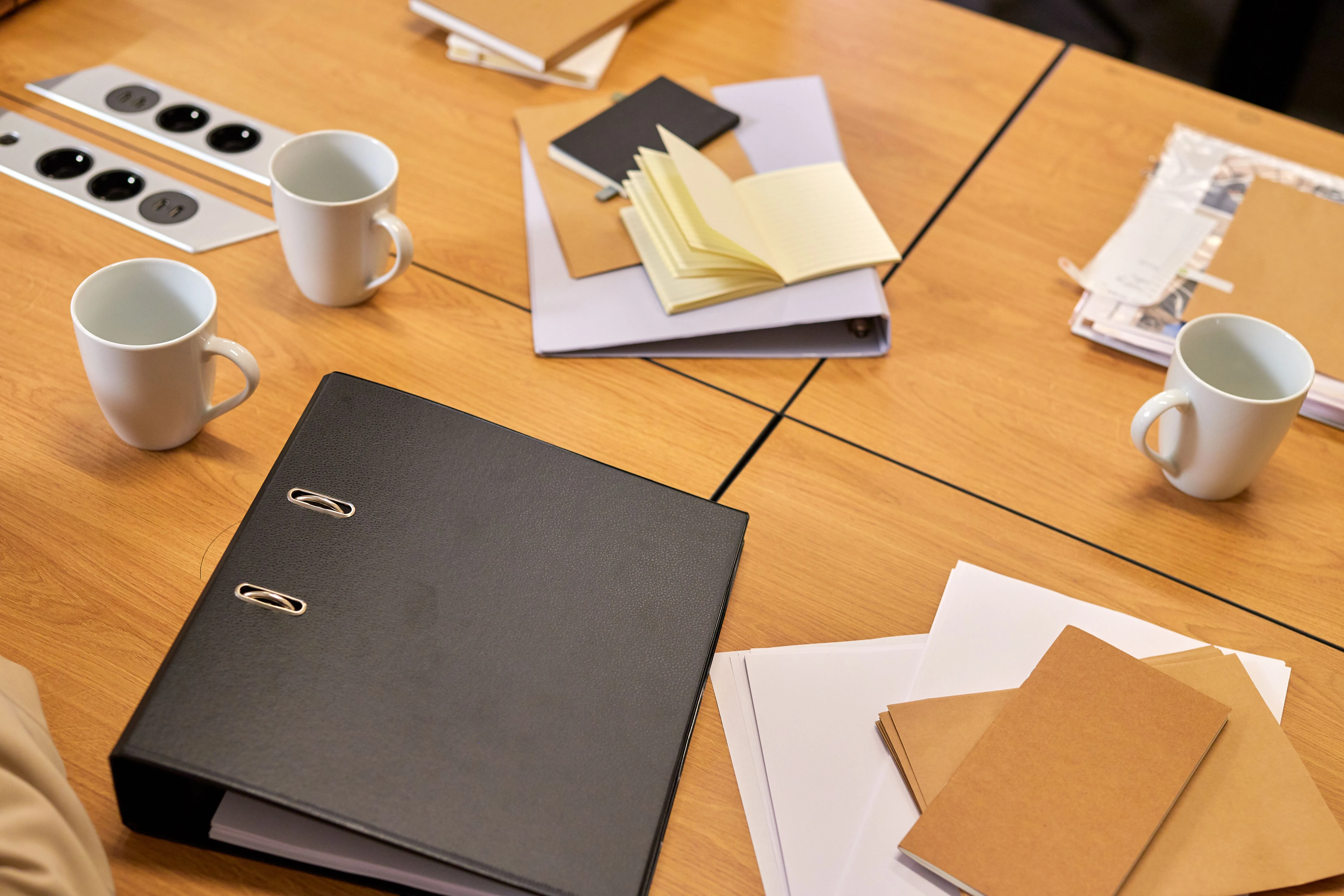 Classeurs, carnets et dossiers posés sur une table de réunion.