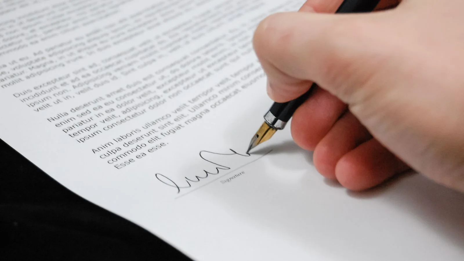 Main signant un document avec un stylo plume, symbole d'un engagement a formaliser.