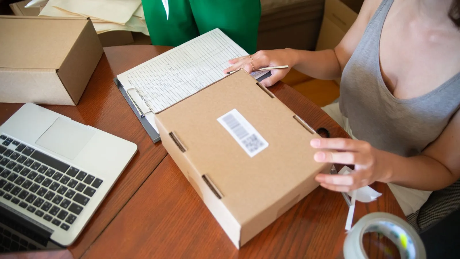 Deux personnes préparent des colis près d'un ordinateur portable, symbole d'une PME qui relie ventes, données et opérations.