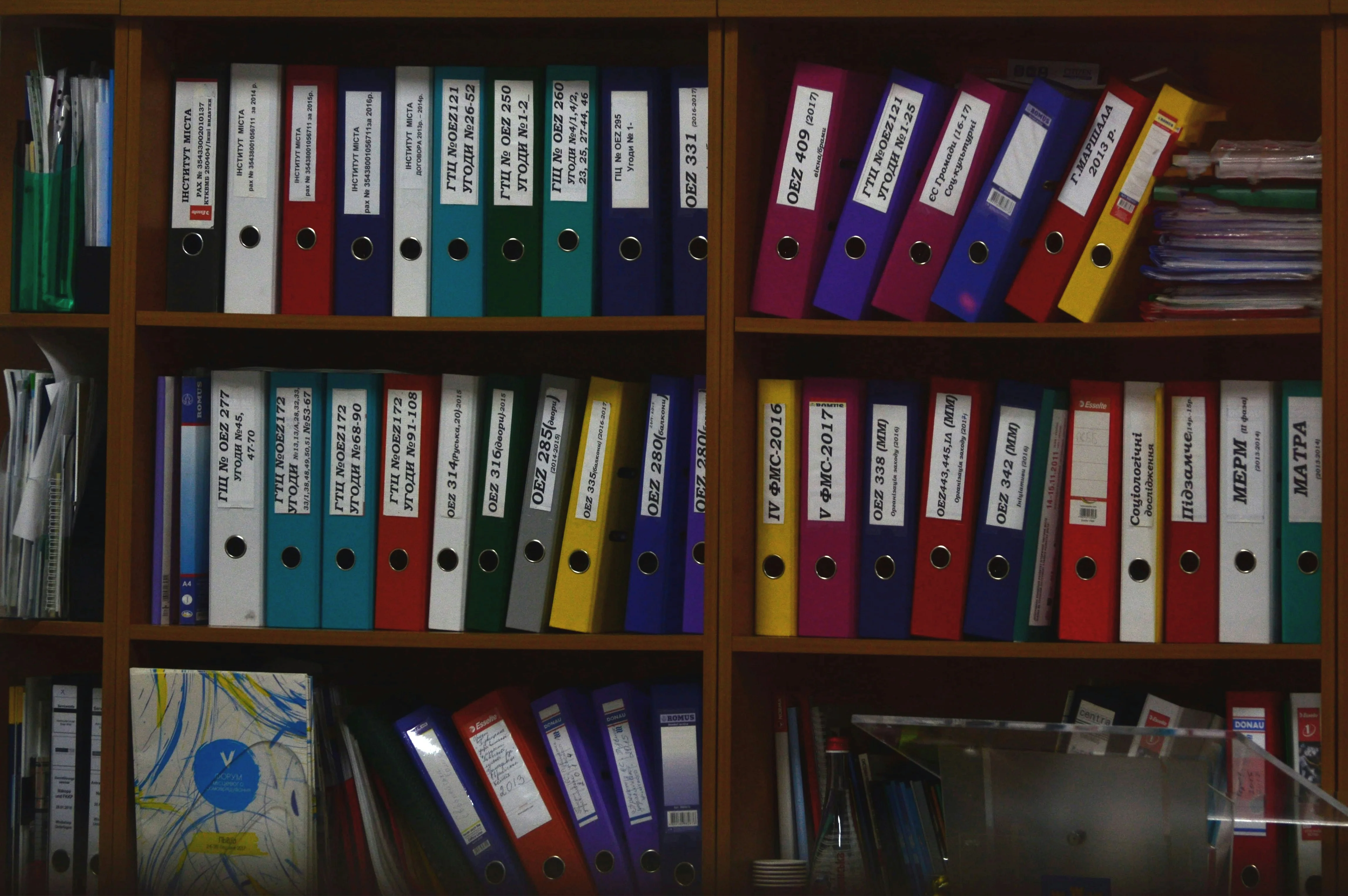 Rangees de classeurs colores sur des etageres de bureau.