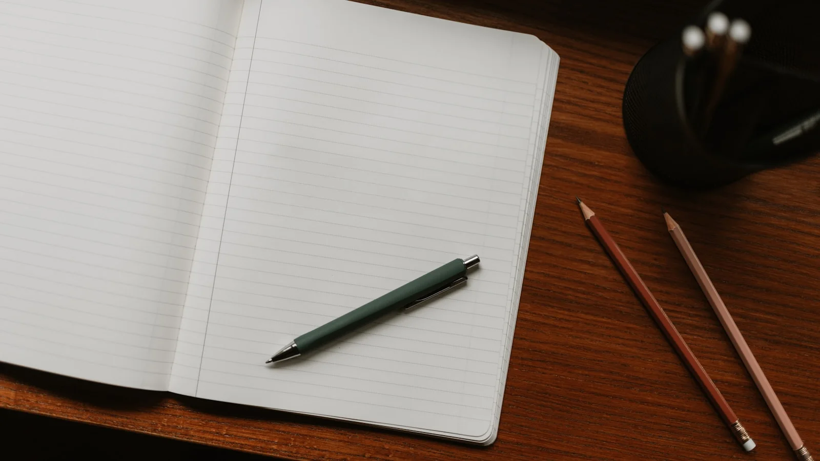 Carnet ouvert posé sur un bureau avec un stylo et des crayons taillés, évoquant la prise de notes manuelle d'un dirigeant qui audite ce que l'IA lui apporte vraiment.