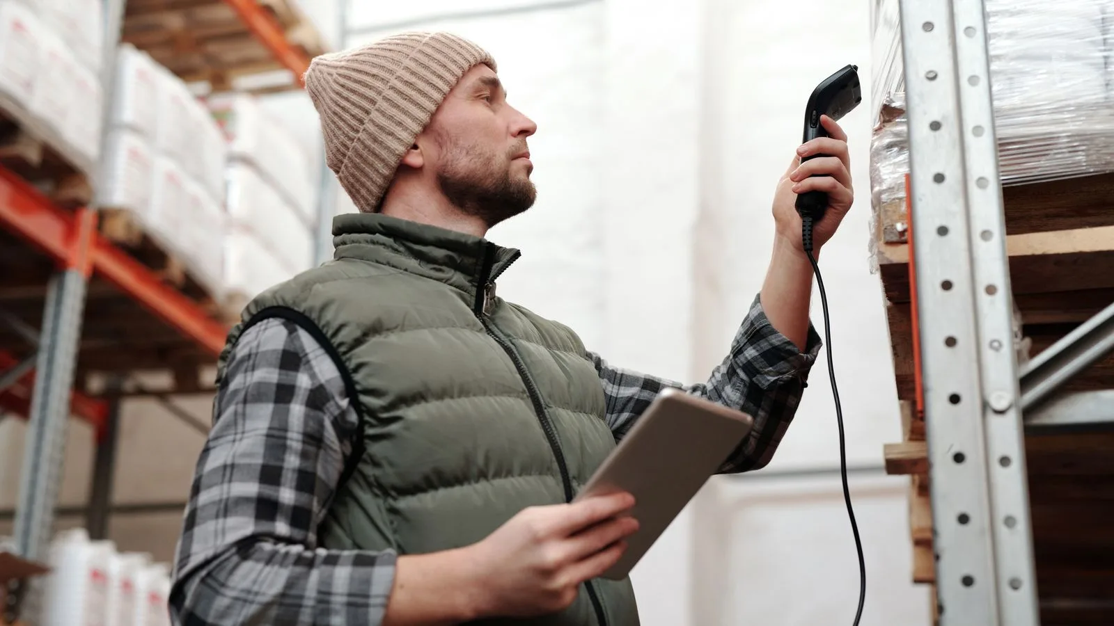Employé d'entrepôt qui vérifie des produits avec un scanner et une tablette.
