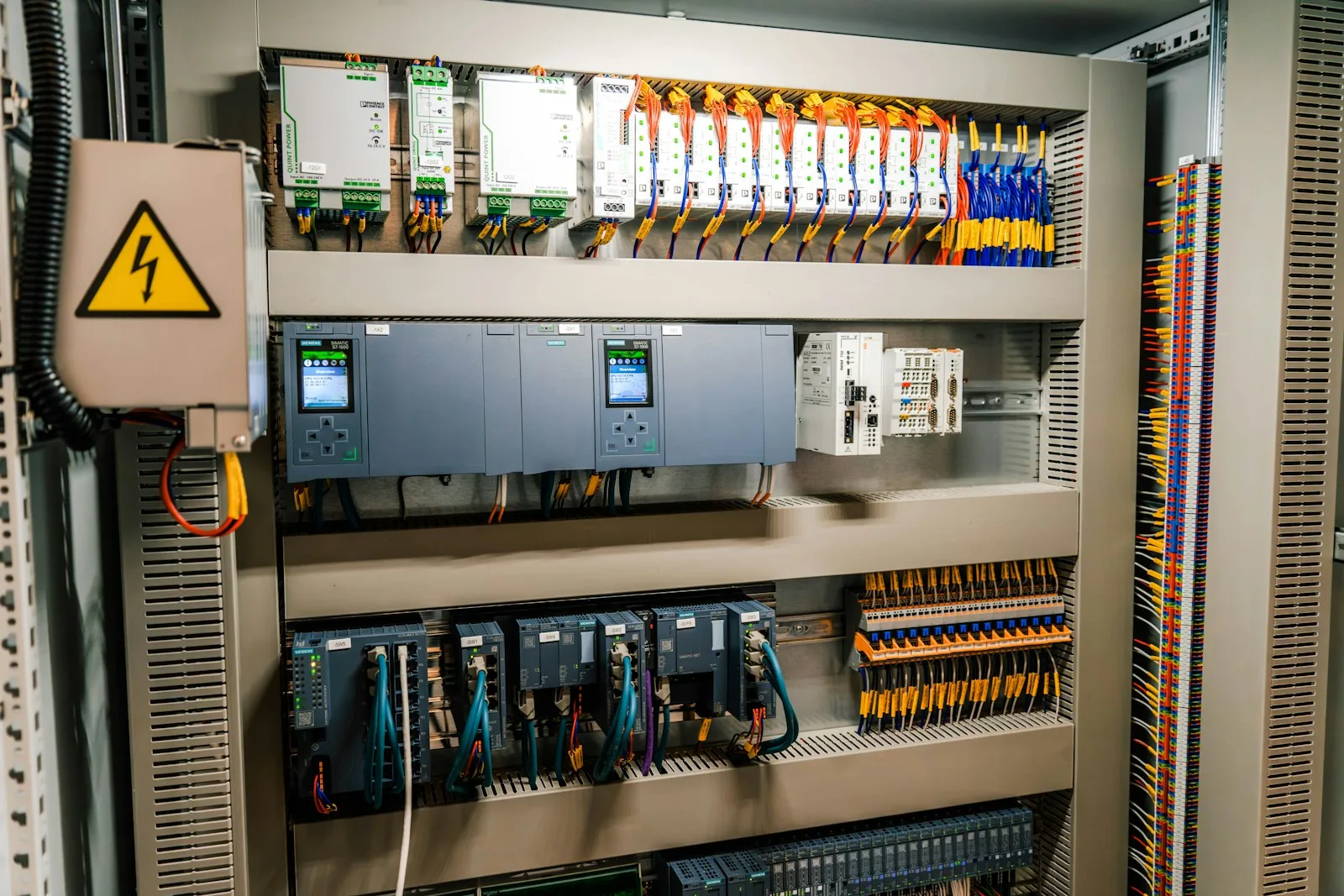 Armoire electrique industrielle ouverte avec automates, cables colores et modules de controle.