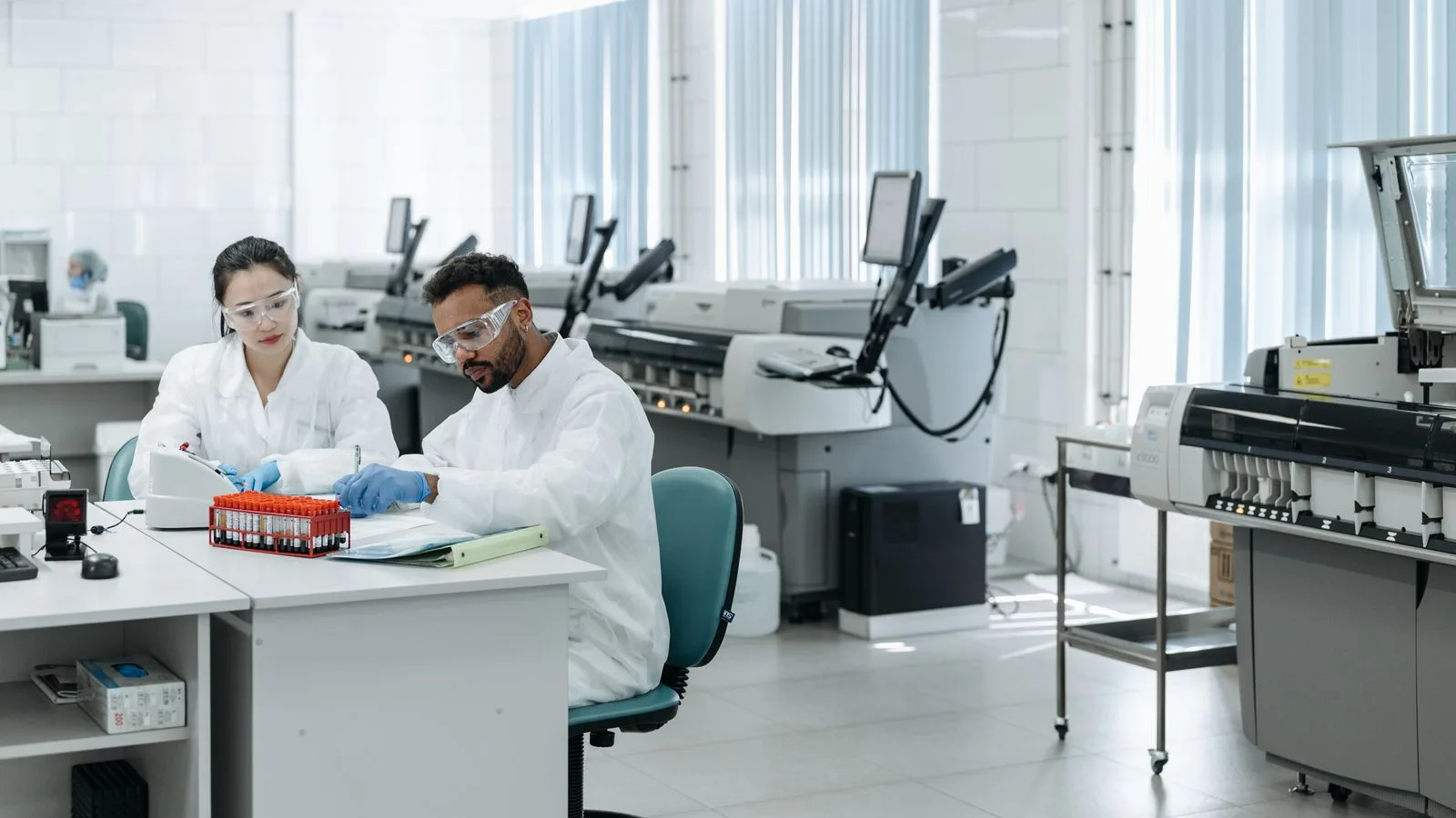 Deux scientifiques en blouse vérifient des documents près d’échantillons dans un laboratoire médical.