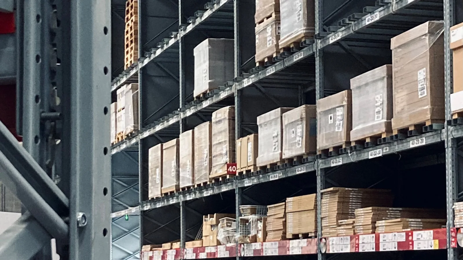 Palettes et cartons étiquetés rangés sur les rayonnages d’un entrepôt logistique.
