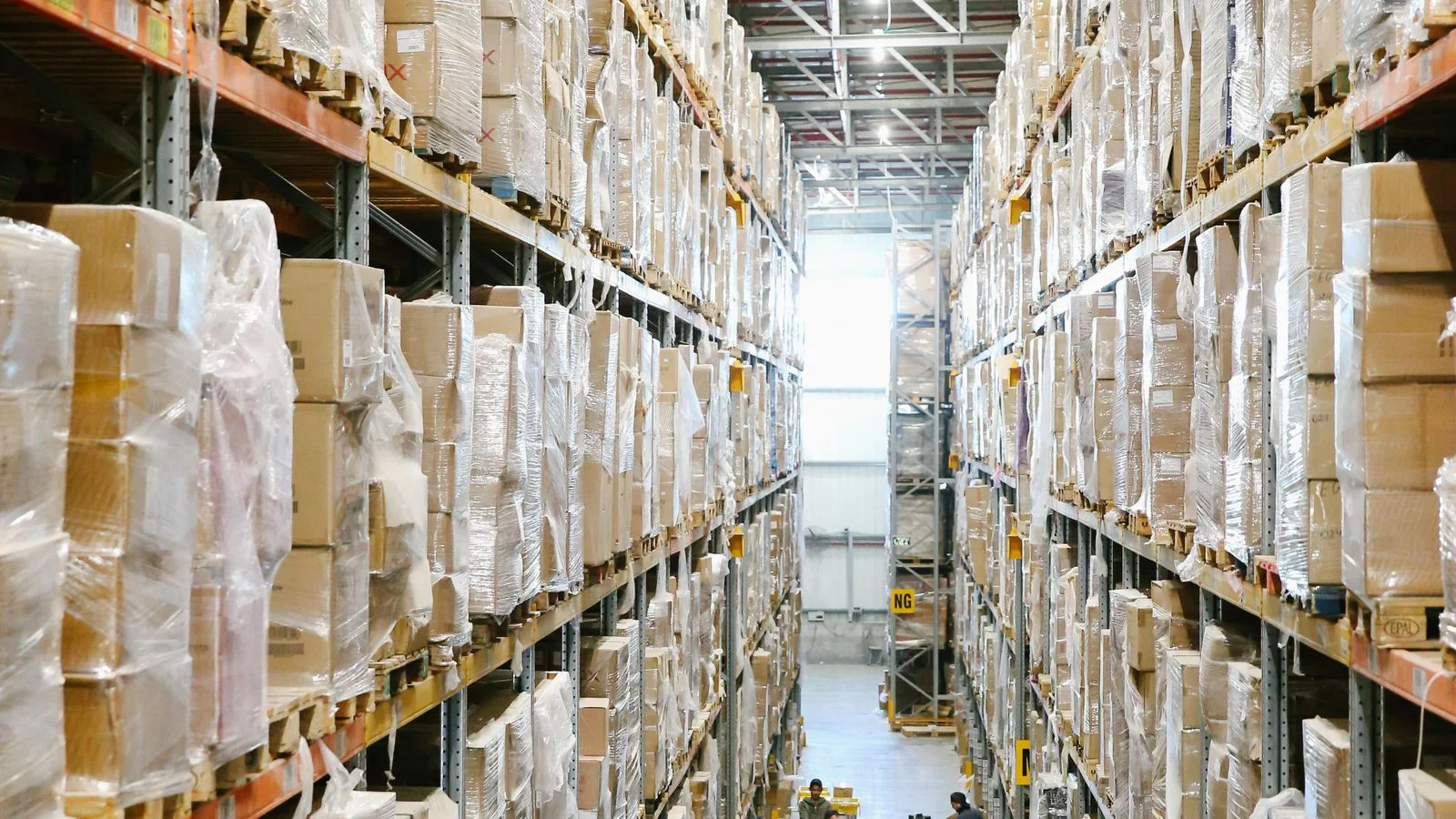 Allées d'entrepôt avec cartons rangés sur des rayonnages, image d'un e-commerce qui dépend du stock réel.