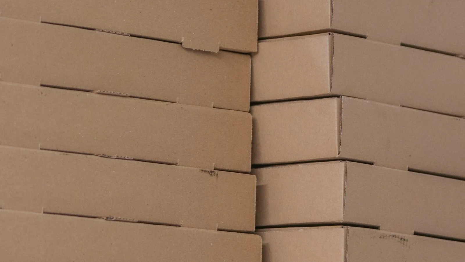 Piles de boîtes alimentaires en carton brun rangées dans une réserve.