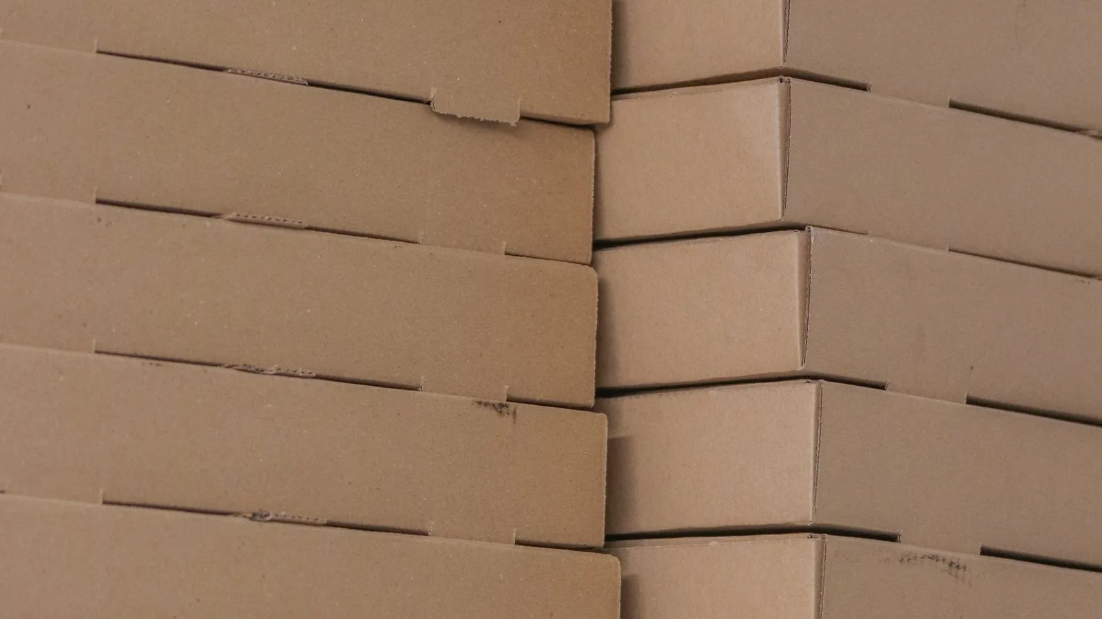 Piles de boîtes alimentaires en carton brun rangées dans une réserve.