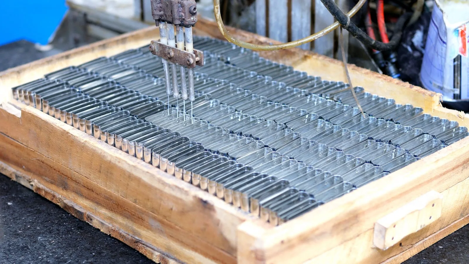 Machine automatisée au-dessus de rangées de petites pièces métalliques.