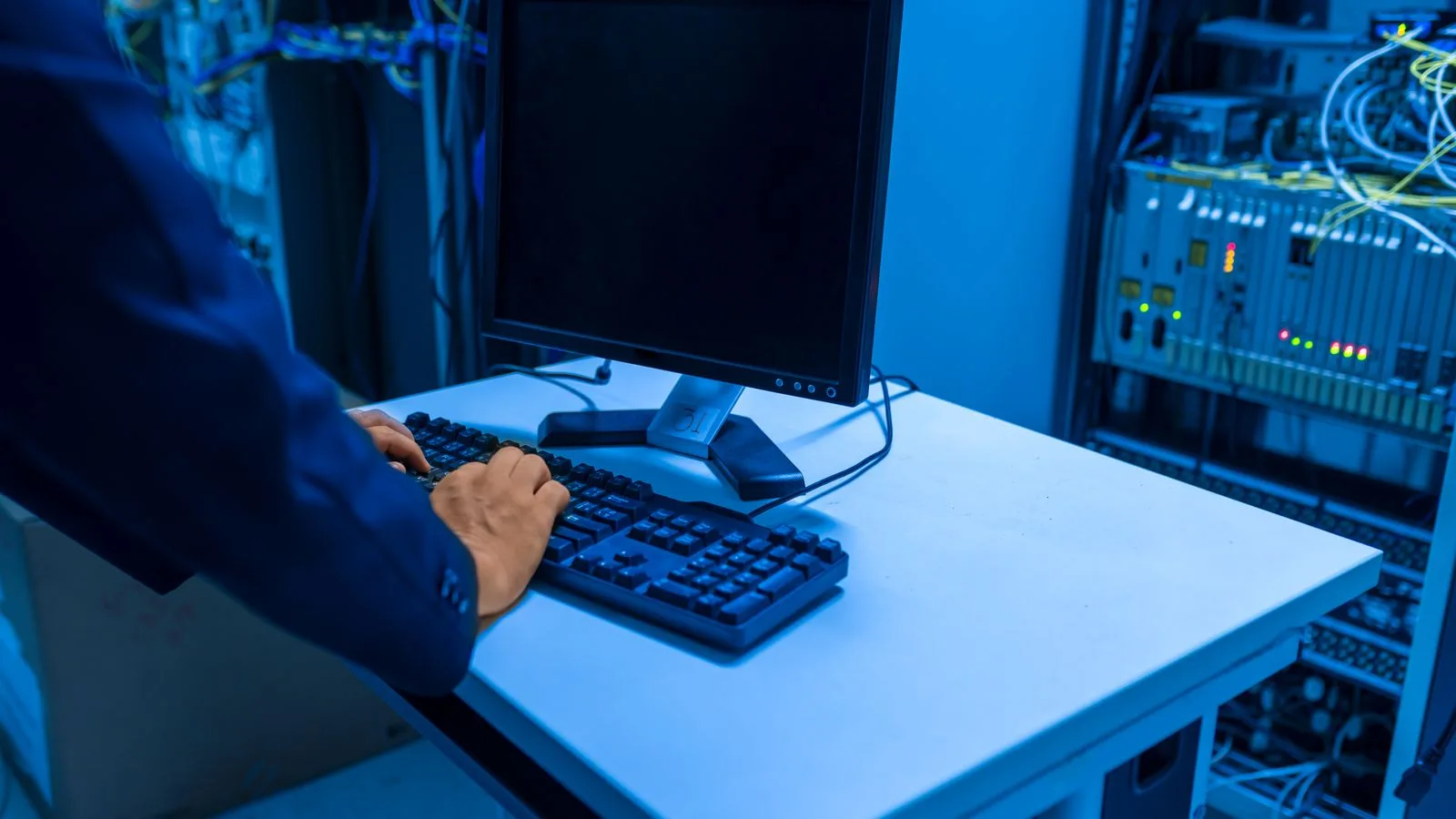 Technicien travaillant dans une salle serveur devant des baies informatiques.