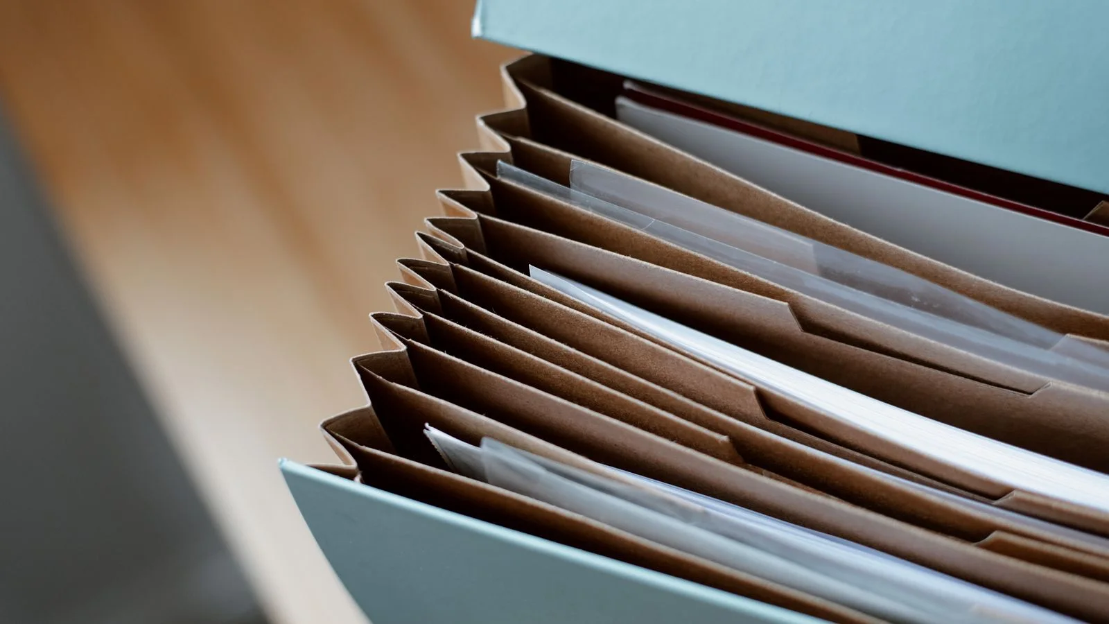 Un porte-documents ouvert avec des dossiers papier classés sur une table en bois.