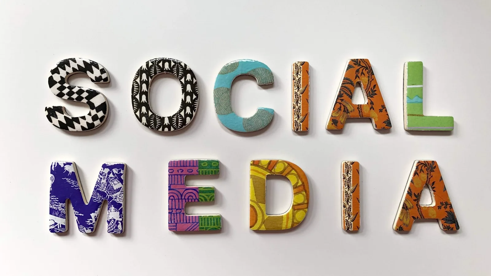 Lettres colorees formant les mots Social Media sur un mur blanc.