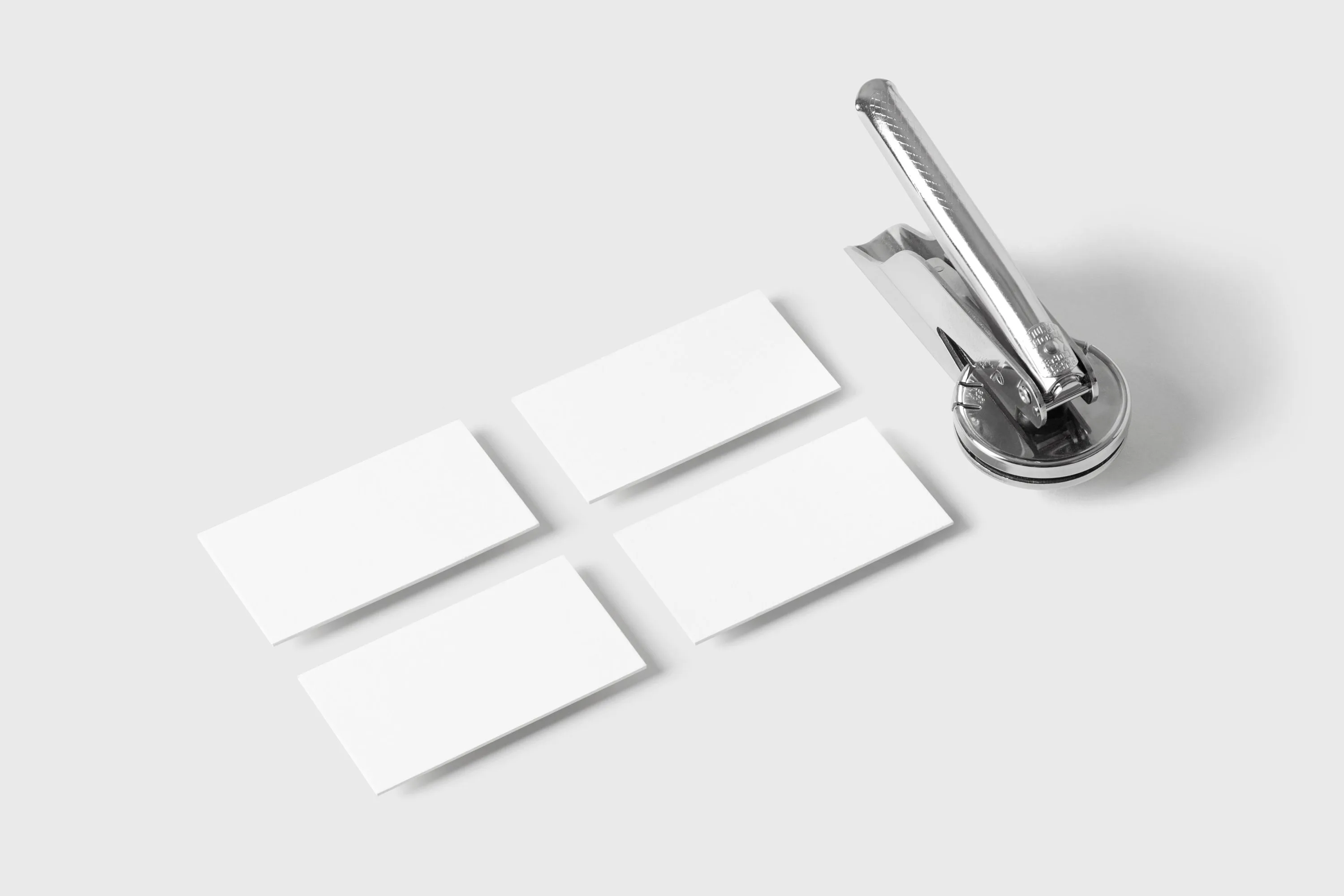 Cartes de visite blanches et pince à embossage sur un bureau gris clair, symbolisant les contacts commerciaux à qualifier.