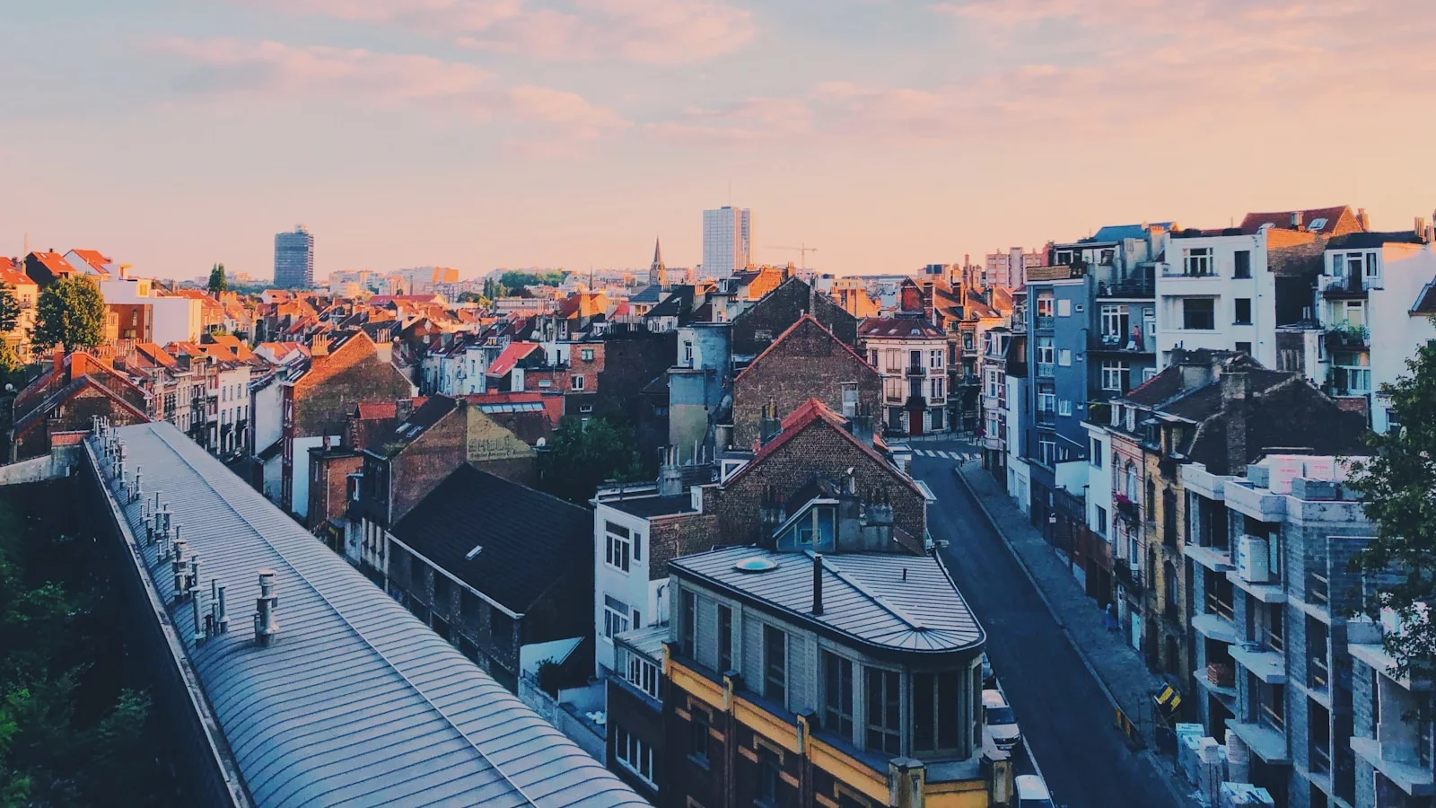 Vue panoramique de Bruxelles au crépuscule, tons orangés sur les toits du quartier d'Ixelles, évoquant l'écosystème belge des agences IA.