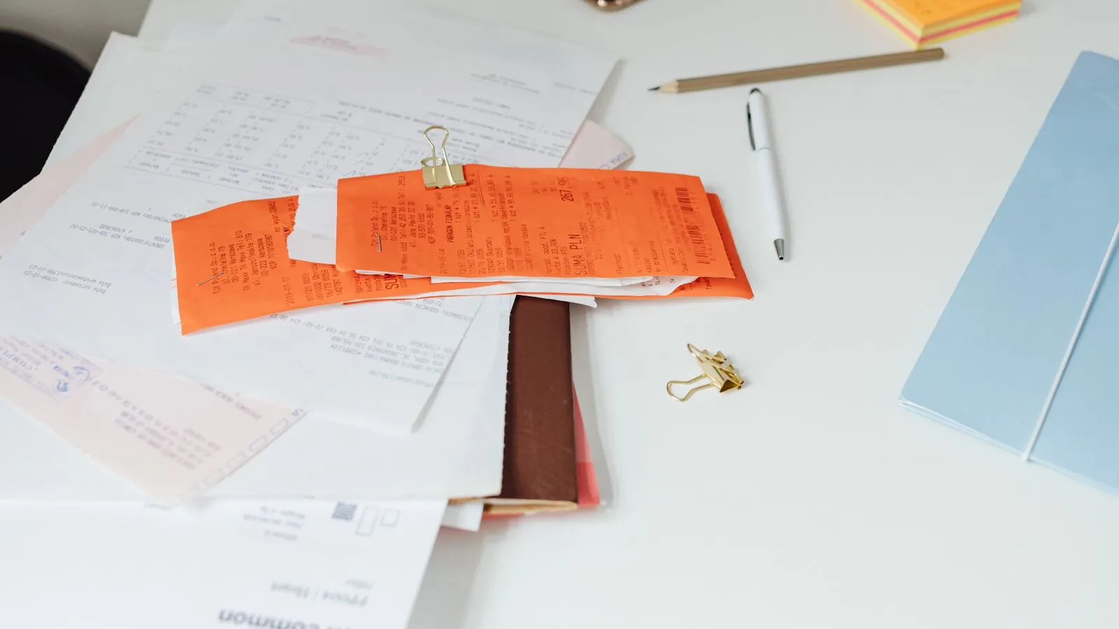 Reçus, documents administratifs et fournitures de bureau ranges sur une table claire.