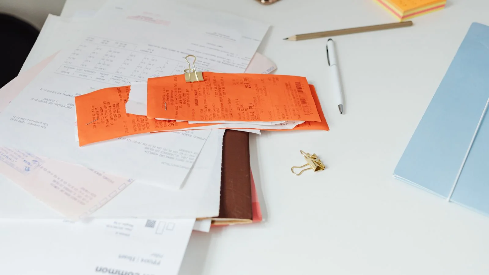 Reçus, documents administratifs et fournitures de bureau ranges sur une table claire.