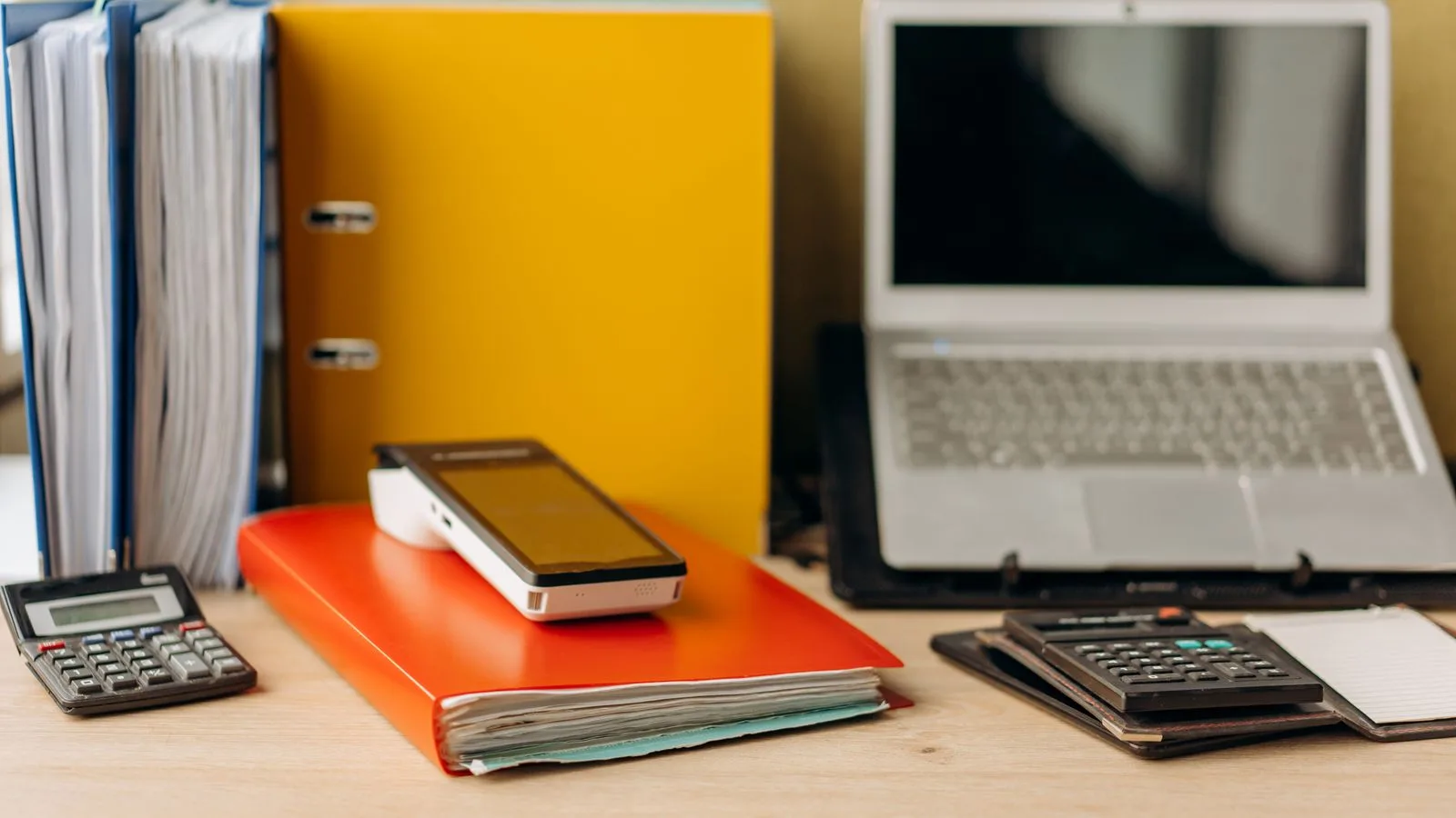 Calculatrice, dossiers et documents organisés sur un bureau pour préparer une décision de facturation.