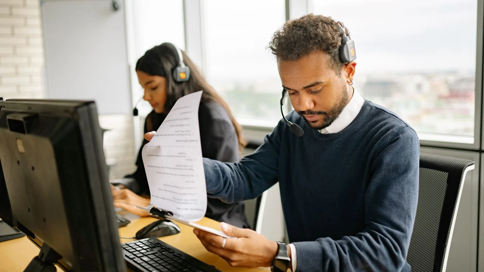 Collaborateurs de service client avec casques, documents et postes de travail dans un bureau.