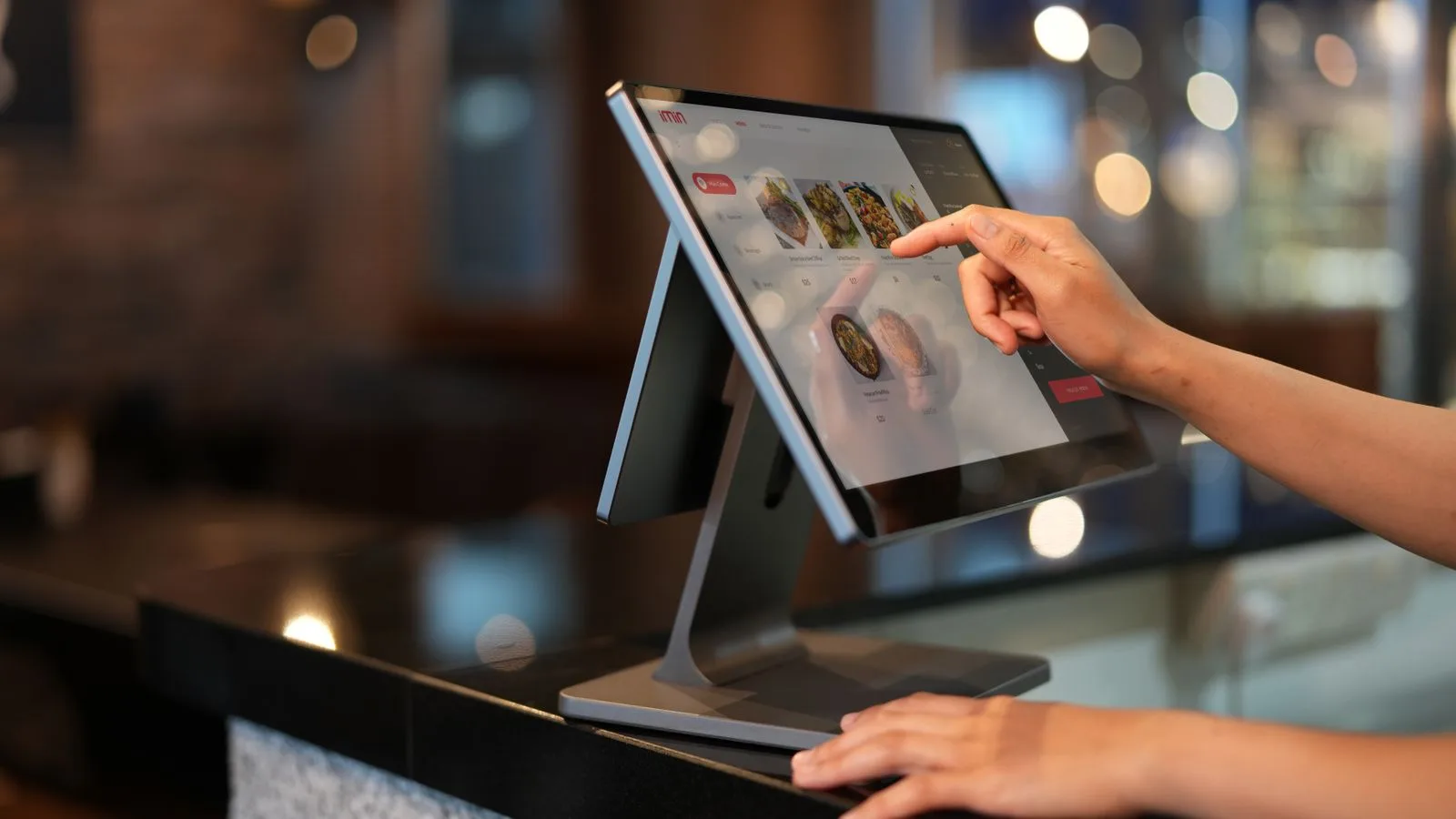 Main utilisant un écran de caisse tactile dans un établissement horeca.
