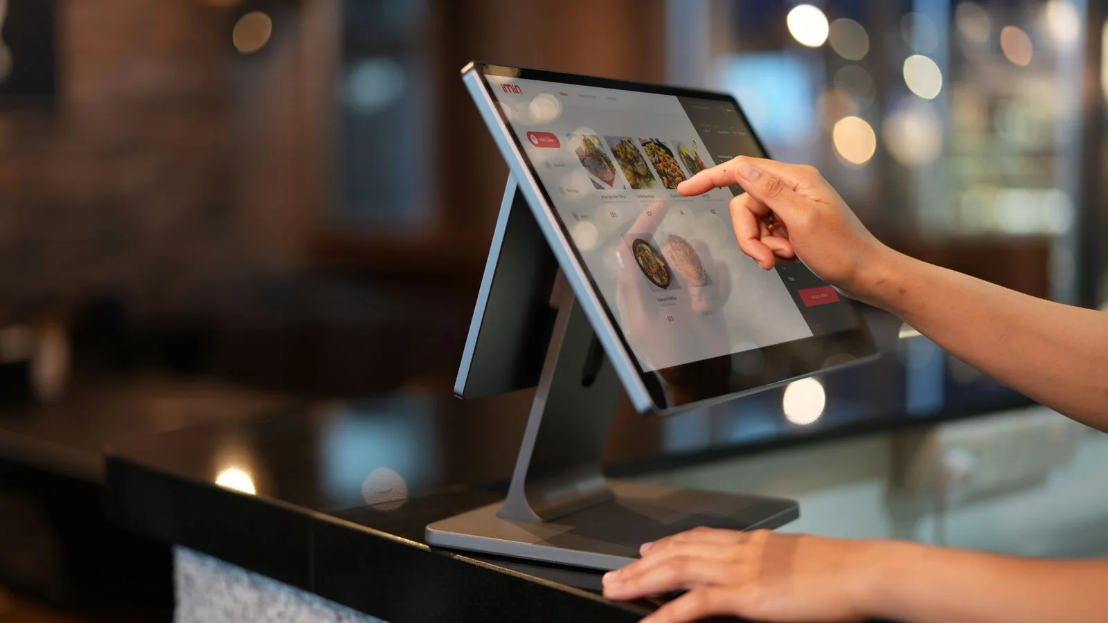Main utilisant un écran de caisse tactile dans un établissement horeca.