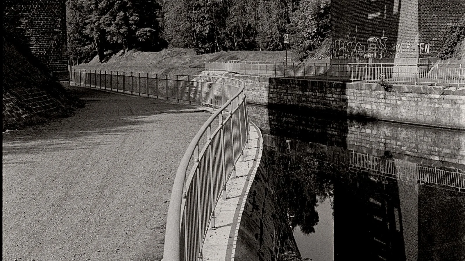 Pont ferroviaire en pierre au-dessus d’un canal à La Louvière, photographié en noir et blanc.