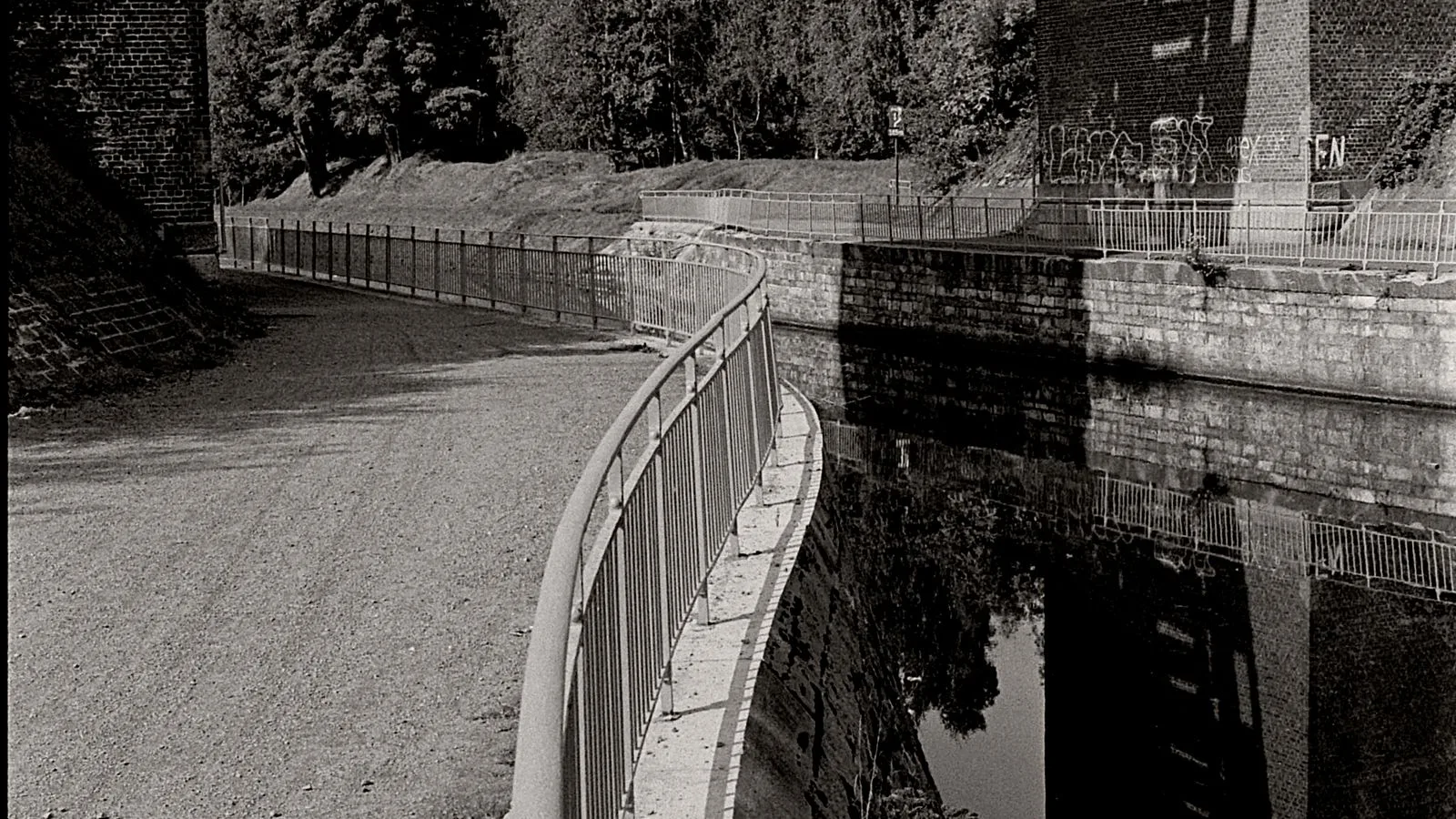 Pont ferroviaire en pierre au-dessus d’un canal à La Louvière, photographié en noir et blanc.