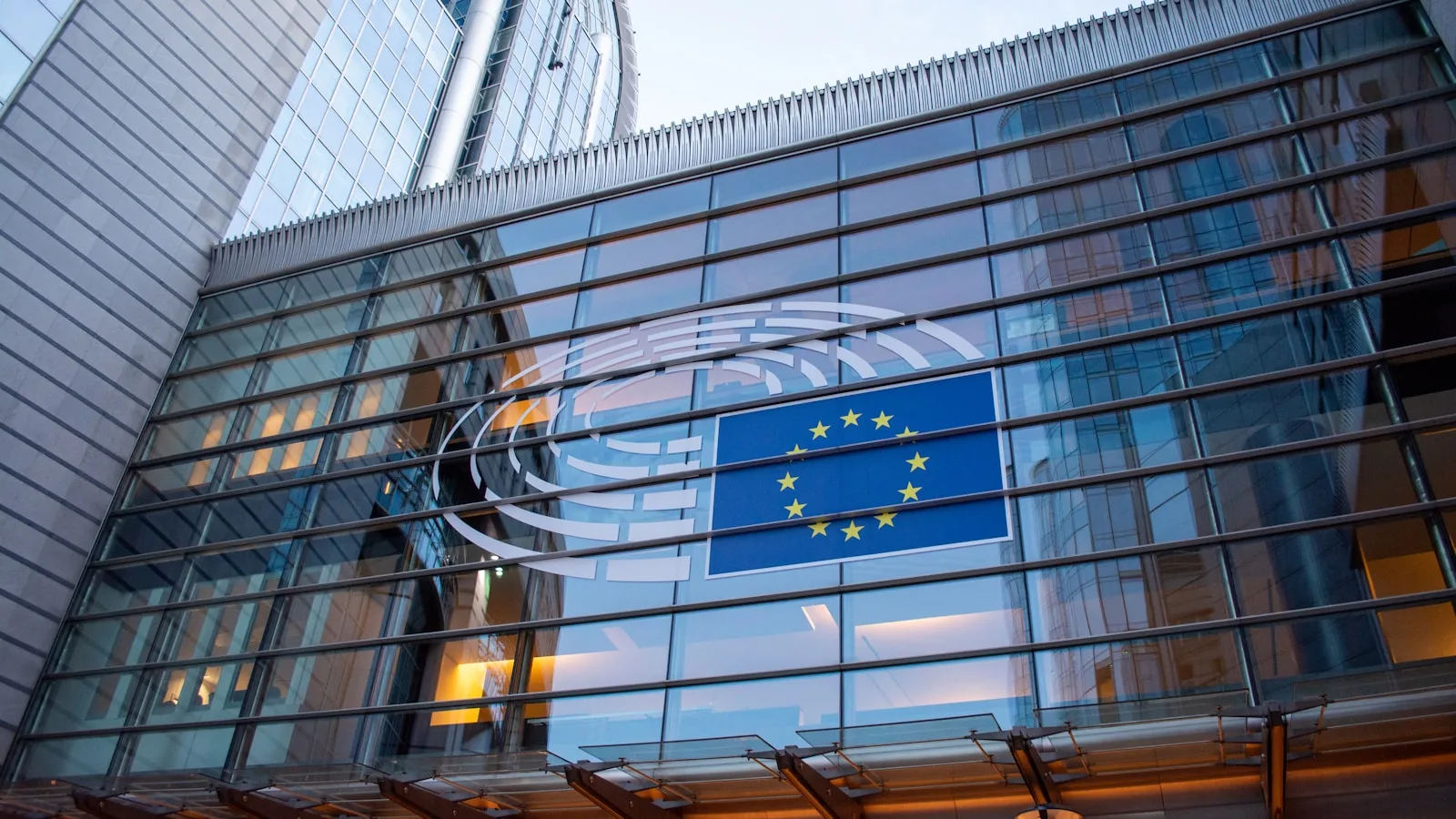 Emblème et drapeau de l'Union européenne sur la façade vitrée du Parlement européen à Bruxelles.