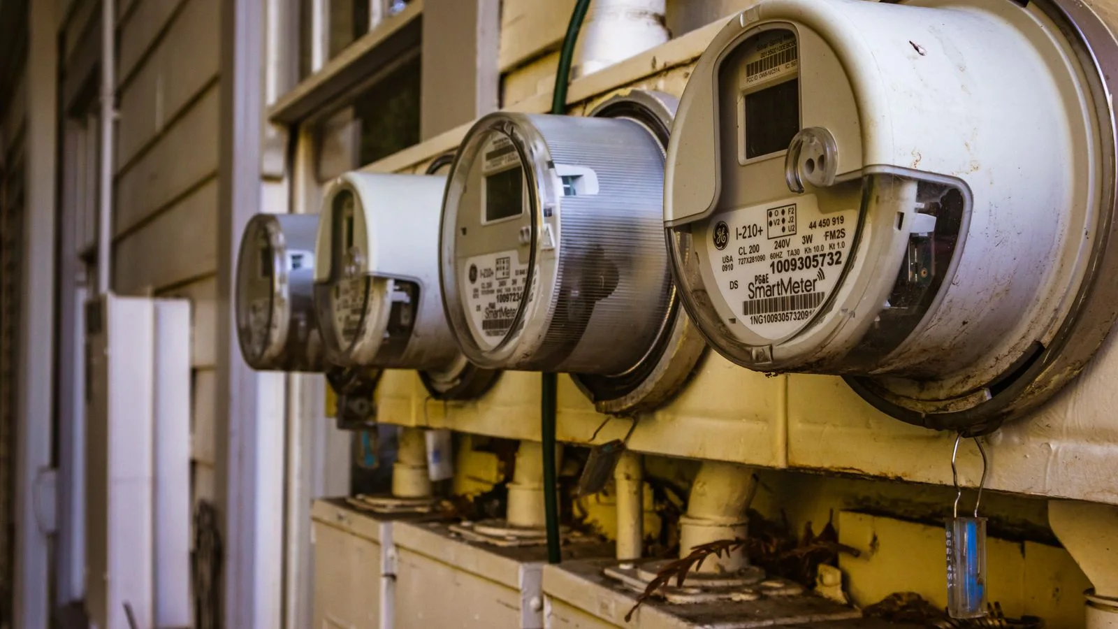 Rangée de compteurs électriques numériques fixés sur un mur extérieur.