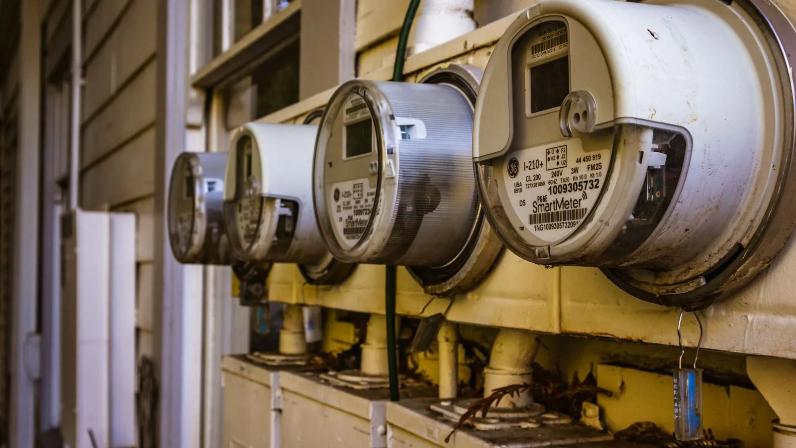 Rangée de compteurs électriques numériques fixés sur un mur extérieur.